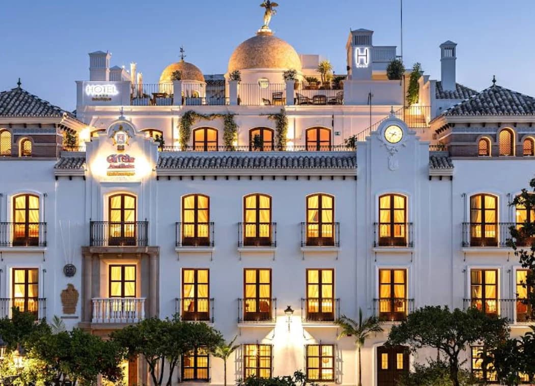Floodlit white facade of Hotel El Pilar at dusk, home to Bermeja Views, Estepona