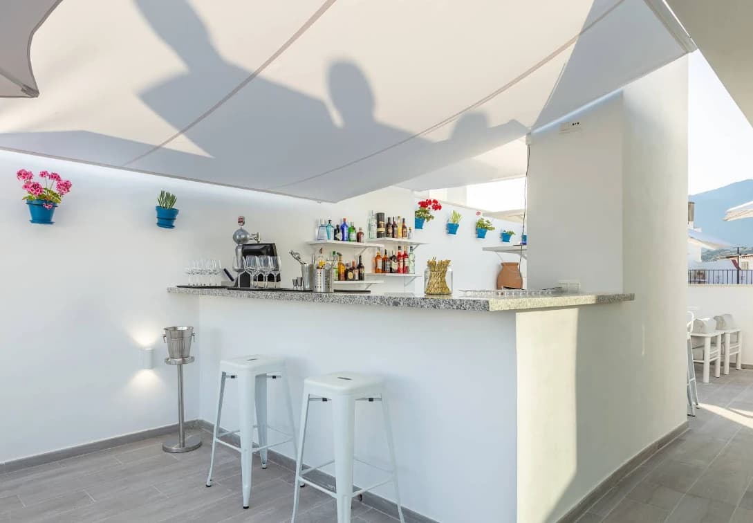 Small white rooftop bar with stools and potted plants at The Old Town Hotel, Estepona
