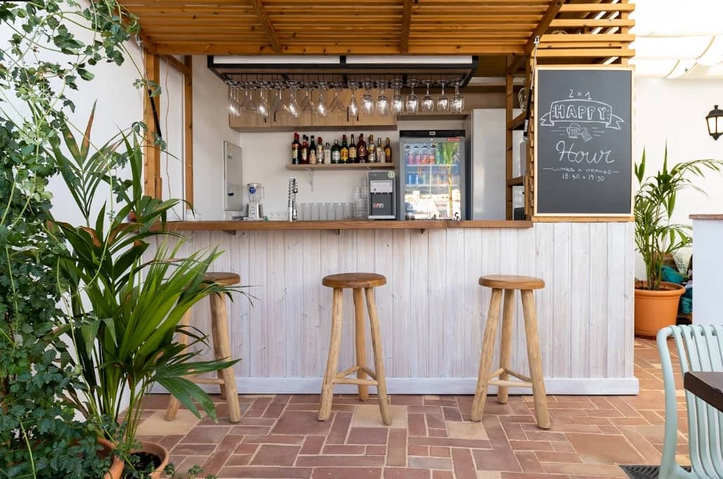 Rustic wooden honesty bar with stools and plants at Hostel Veranera, Estepona