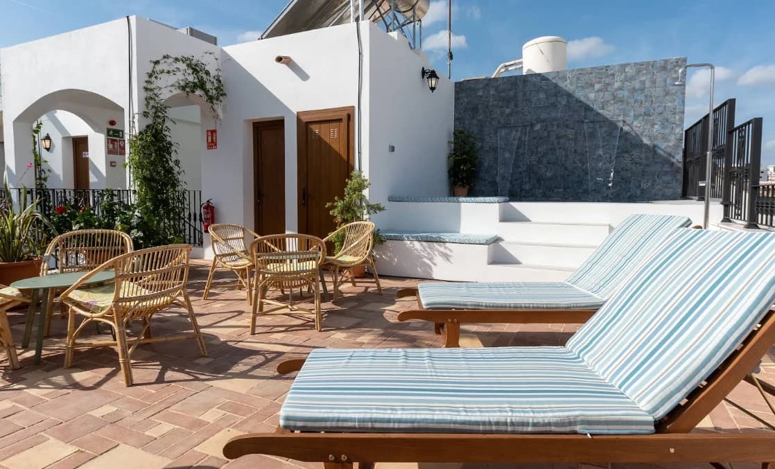 Striped sun loungers and rattan chairs on the sun terrace at Hostel Veranera, Estepona