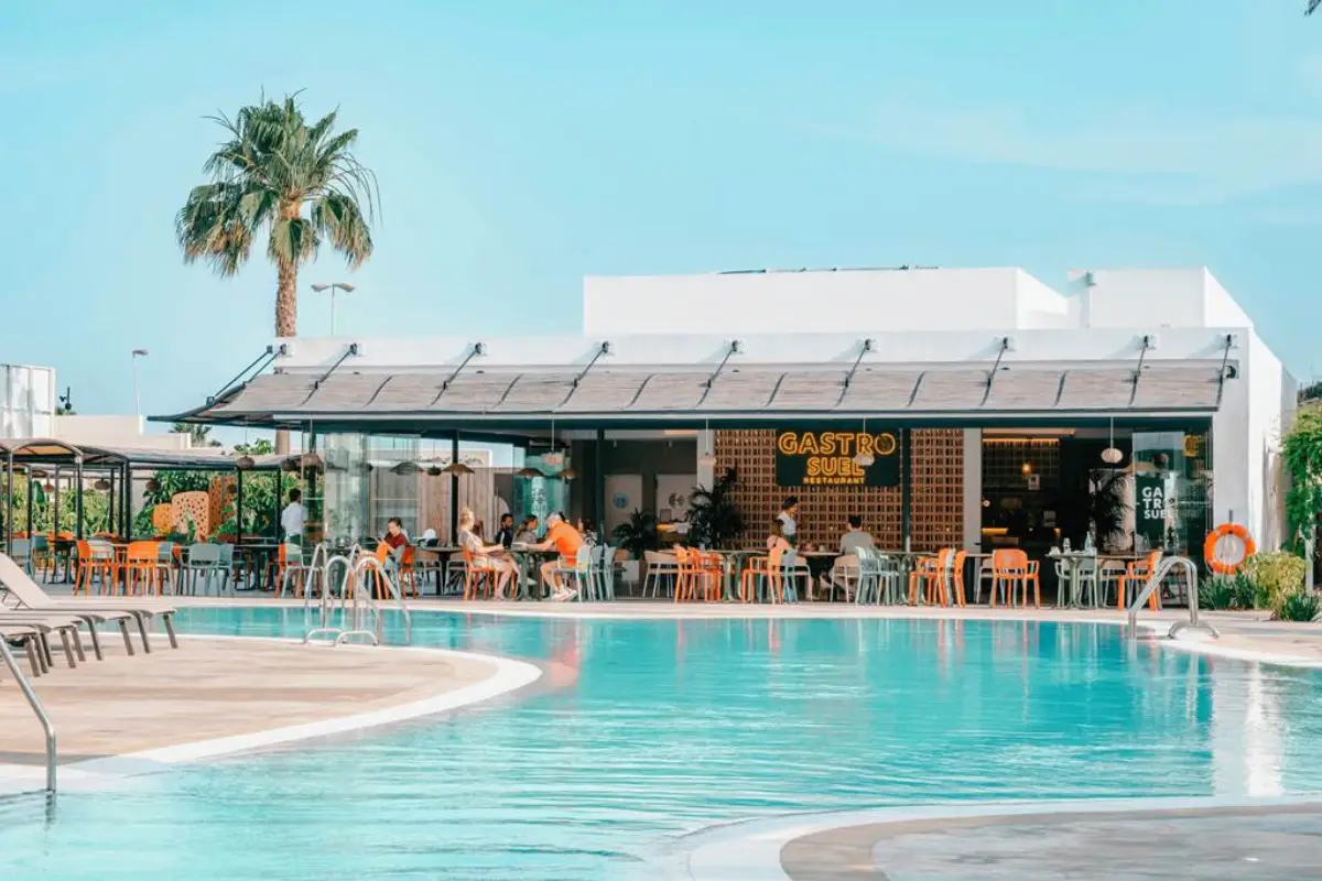 Poolside bar with palm tree and turquoise water at Globales, Fuengirola