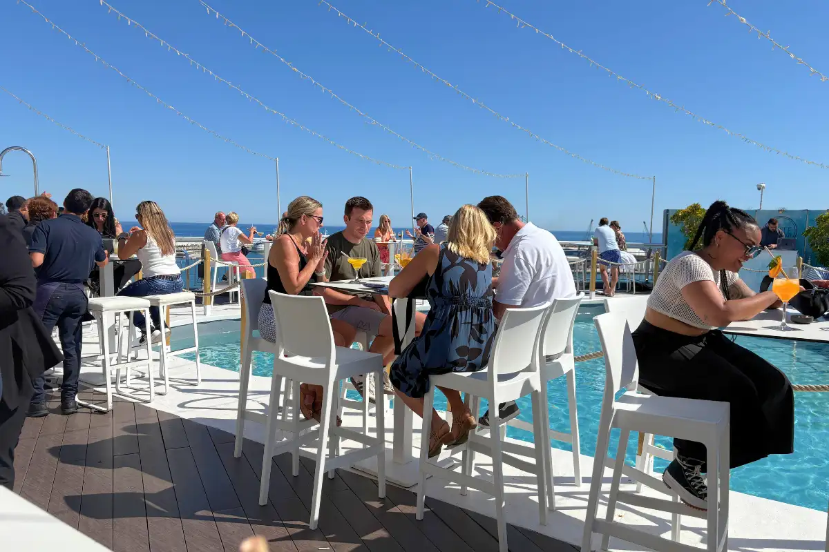 Guests at white poolside tables on the AC Hotel Malaga Palacio rooftop