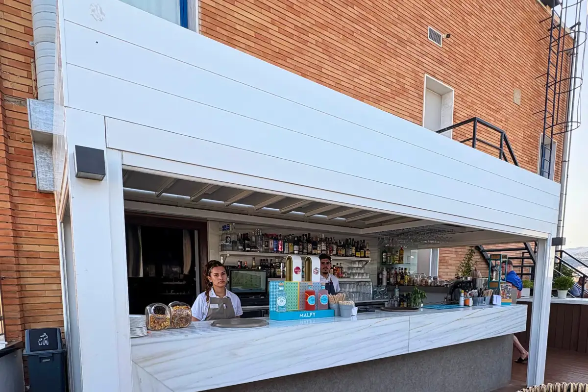 Bartender behind the white poolside bar at Aurea rooftop in Malaga