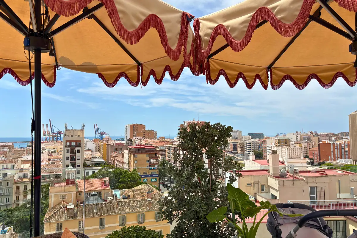 Malaga skyline framed by a parasol fringe at H10 Croma rooftop