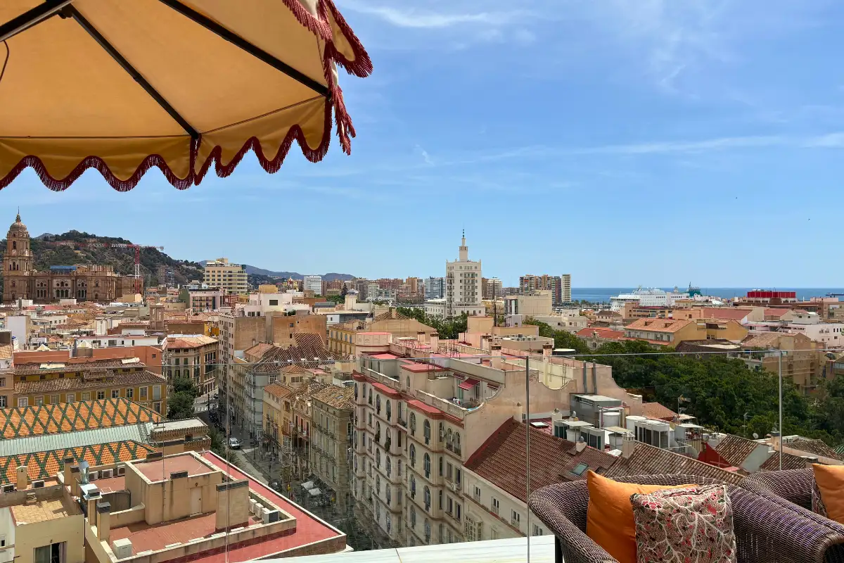 Cushioned seating with views to the sea past a parasol at H10 Croma, Malaga