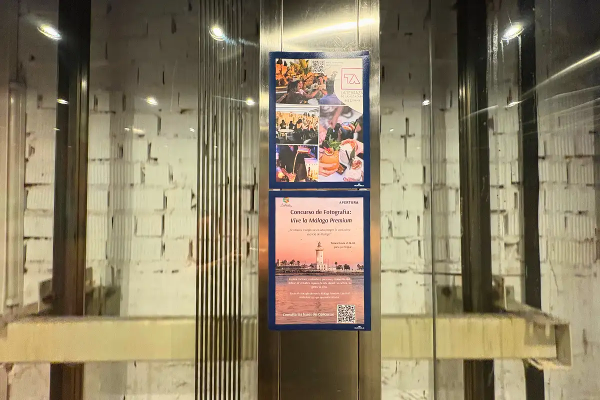 Glass lift with event posters giving access to La Terraza de Alcazaba in Malaga