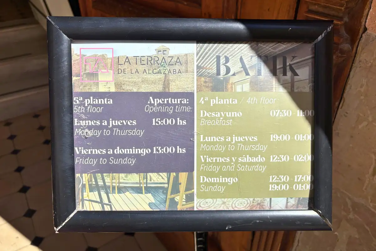 Framed opening hours sign at La Terraza de Alcazaba in Malaga