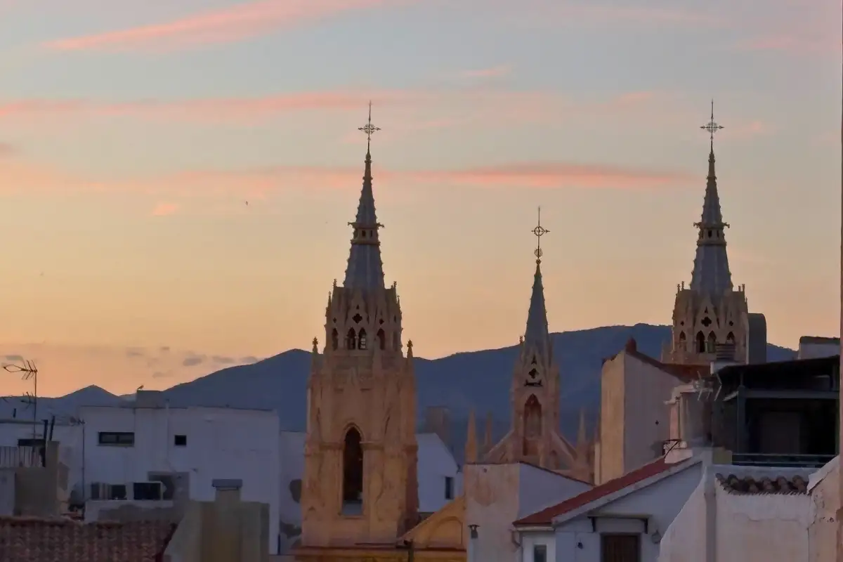 Twin church spires against a pink sunset sky over Malaga from La Terraza de San Juan