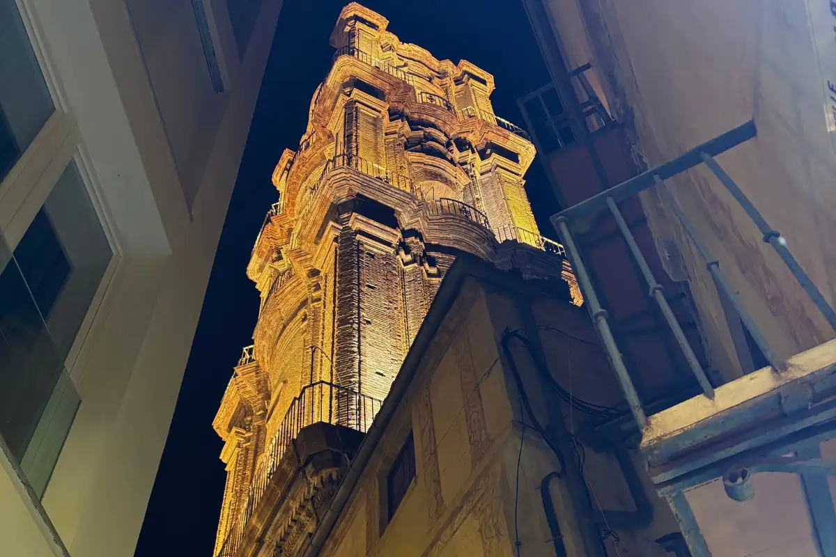 Floodlit stone church tower glowing at night near La Terraza de San Juan in Malaga