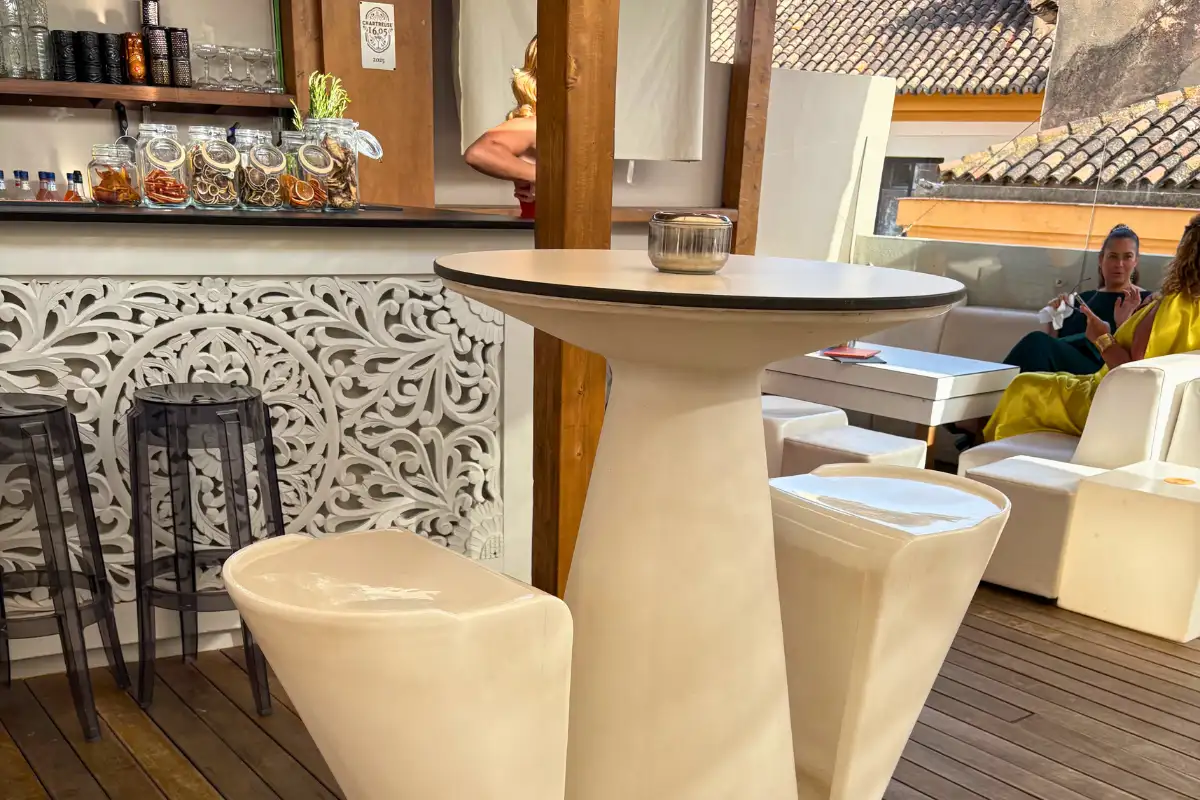 White high table and stools by a carved screen at La Terraza de San Telmo in Malaga