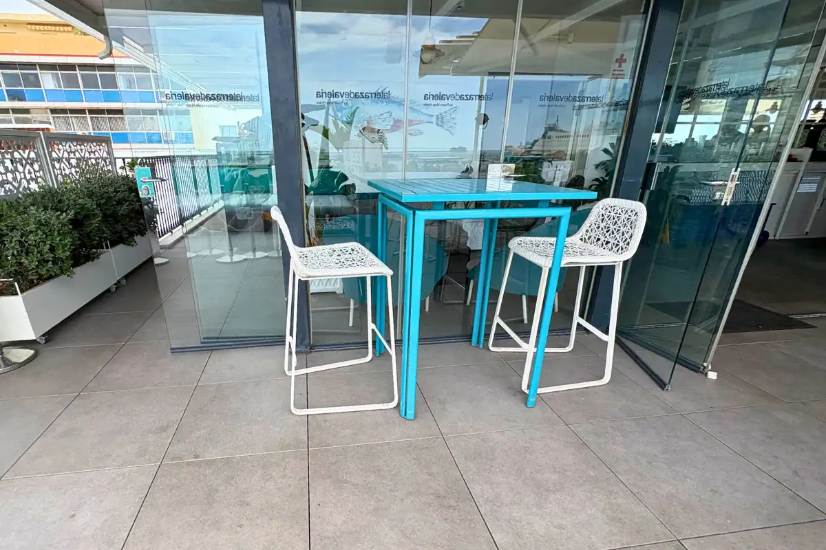 Turquoise high table and stools on the glass-railed terrace at La Terraza de Valeria in Malaga