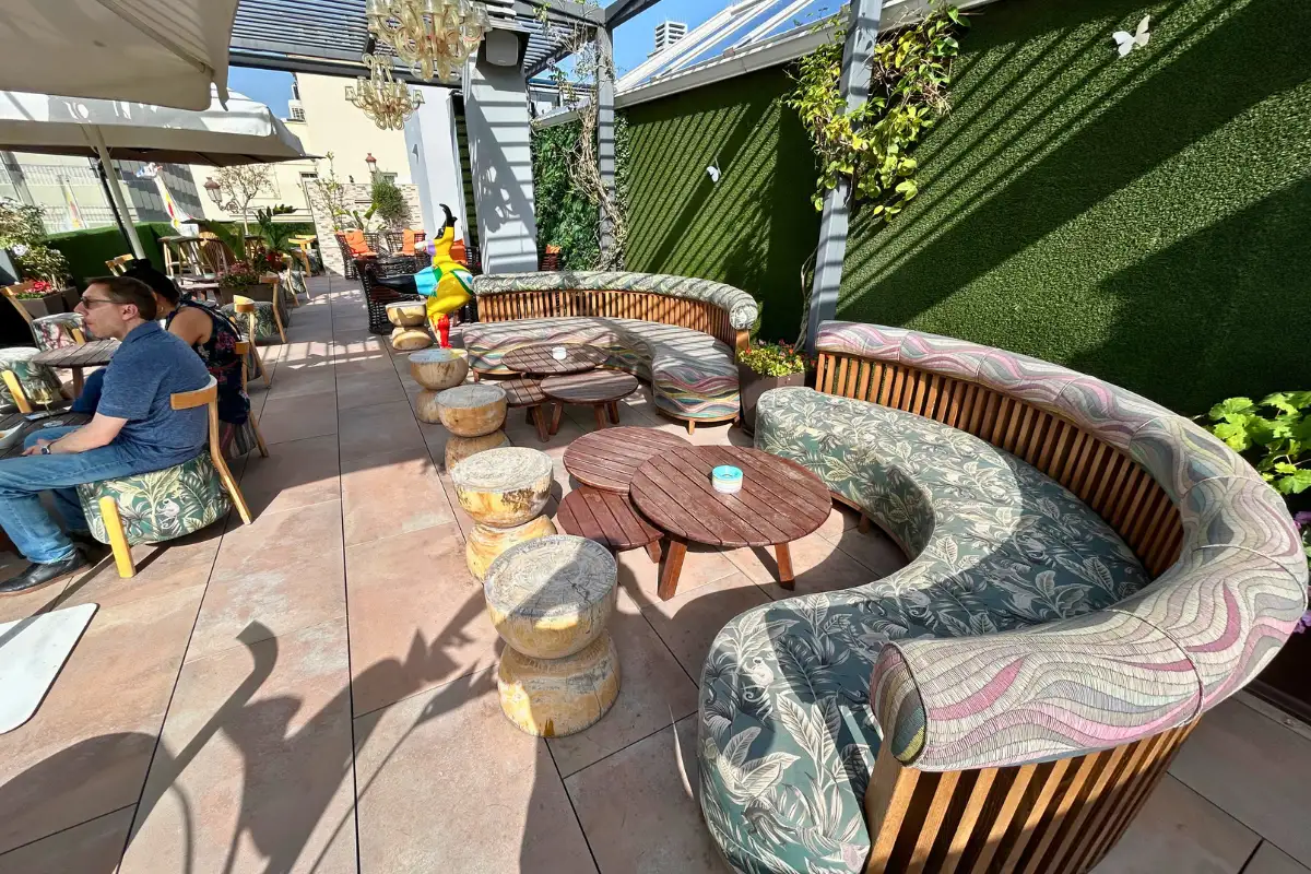 Curved cushioned bench and low tables on the terrace at EFECTO Rooftop, Hotel Mariposa Malaga