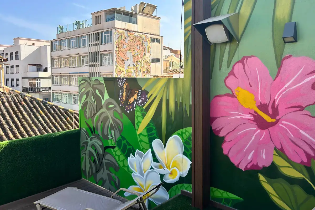 Tropical floral mural beside a sunbed at EFECTO Rooftop, Hotel Mariposa Malaga