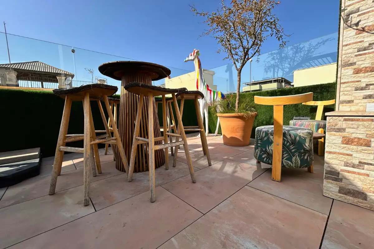 Wooden high tables and bar stools on the terrace at EFECTO Rooftop, Hotel Mariposa Malaga