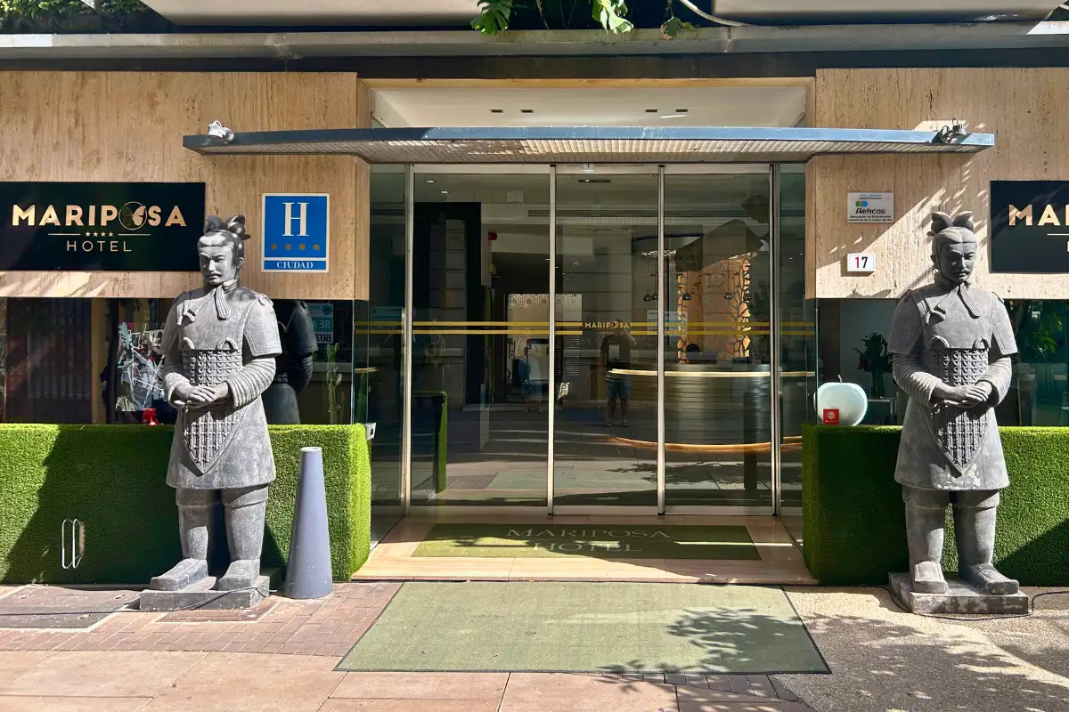 Glass entrance flanked by terracotta warrior statues at Hotel Mariposa in Malaga