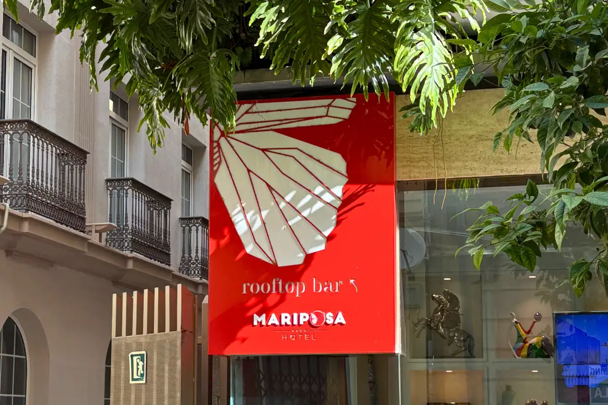 Red Mariposa rooftop bar sign hanging on a Malaga street facade