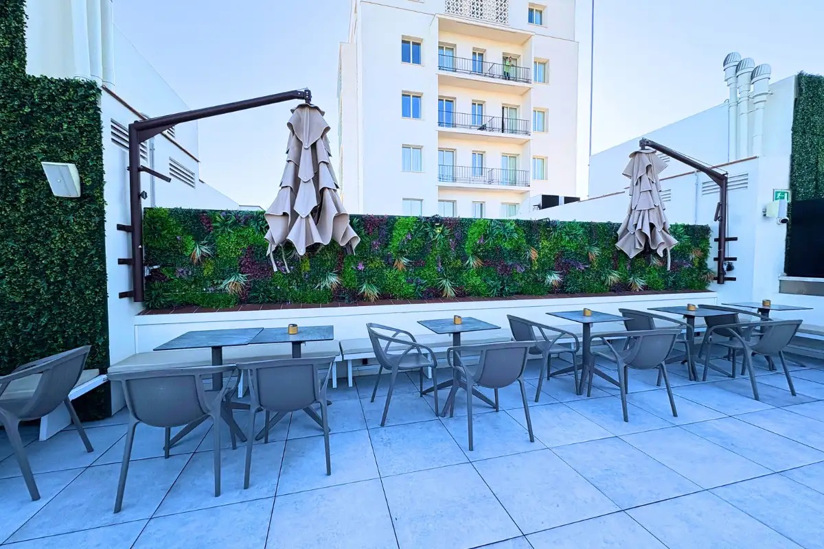 Terrace dining tables with folded parasols and hedge backdrop at Lolita Skyview in Malaga