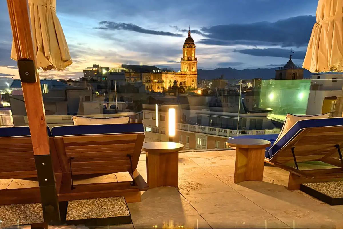Sun loungers and pool lit up at night with the Malaga cathedral beyond at ME Malaga