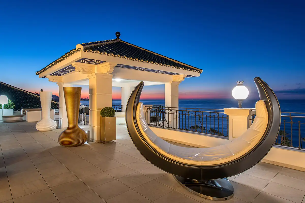 Lit gazebo and curved seat with sea views at dusk at Media Luna, Gran Hotel Miramar, Malaga