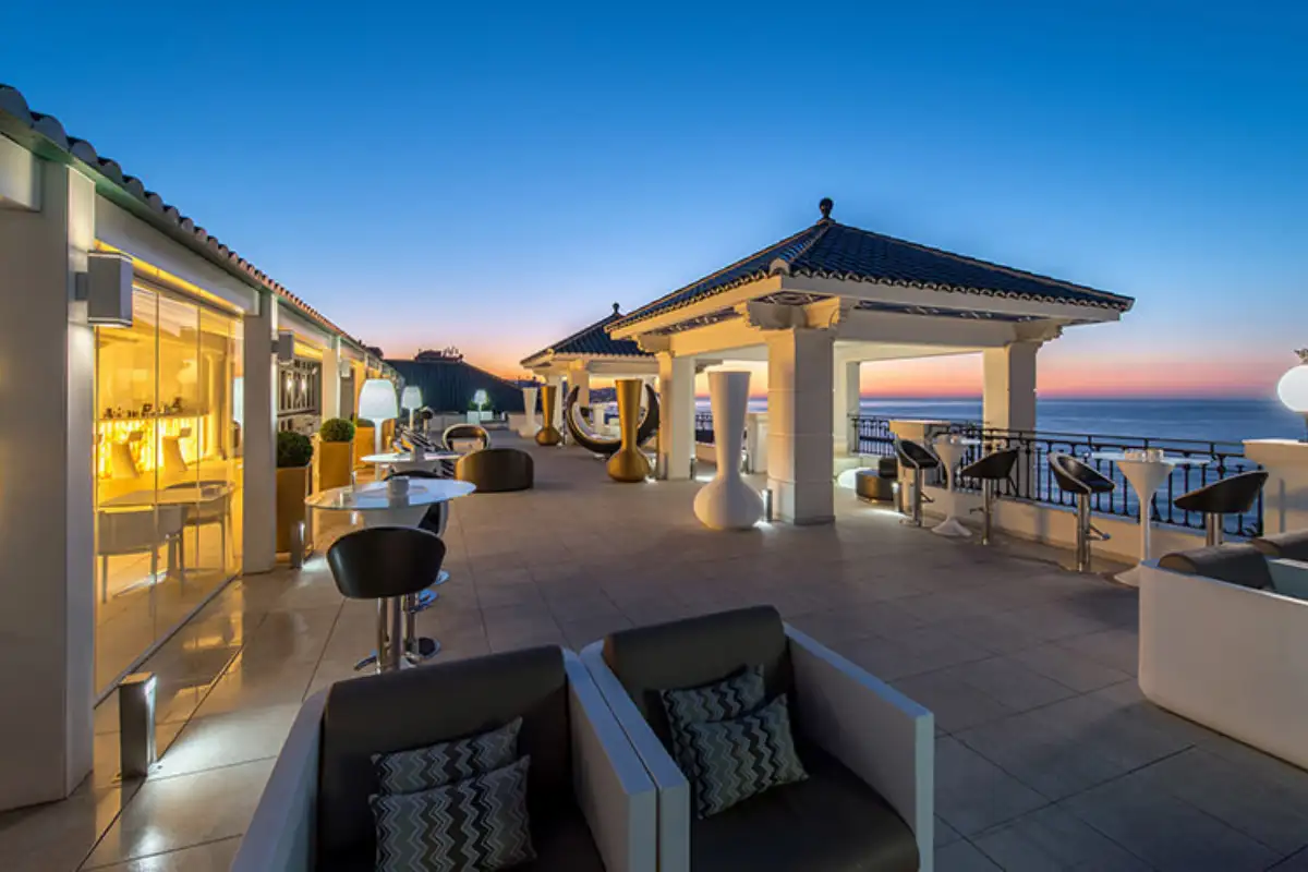 Lounge sofas and gazebos along the terrace at dusk at Media Luna, Gran Hotel Miramar, Malaga