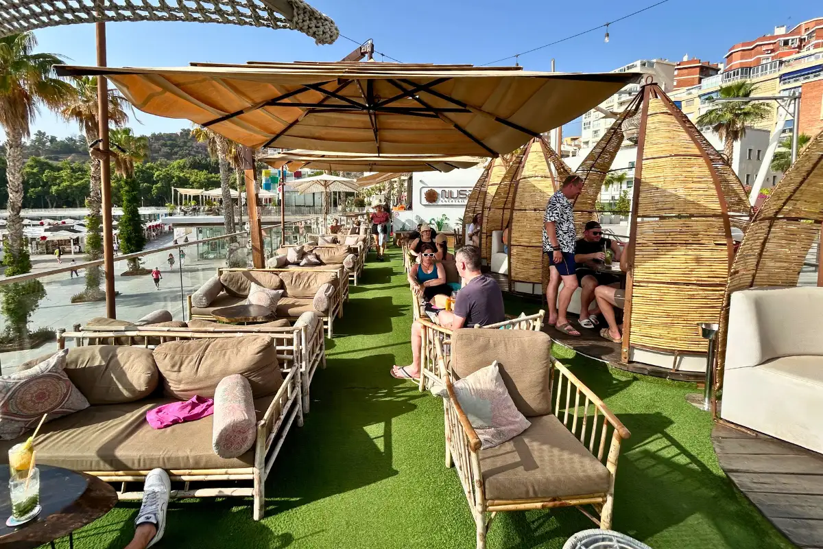 Bamboo cabanas and cushioned lounge seating on the terrace at Nusa, Malaga