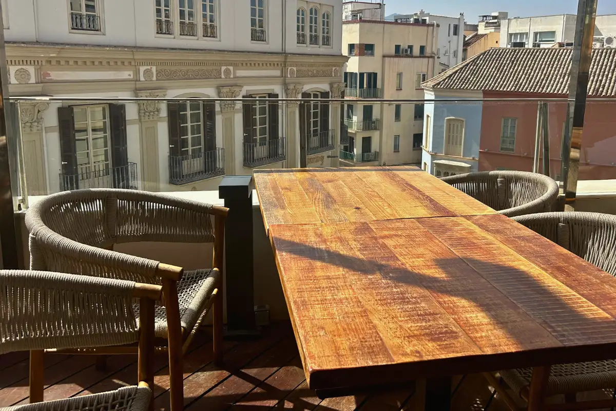 Long wooden communal table on the rooftop terrace overlooking Malaga at Terraza Catedral