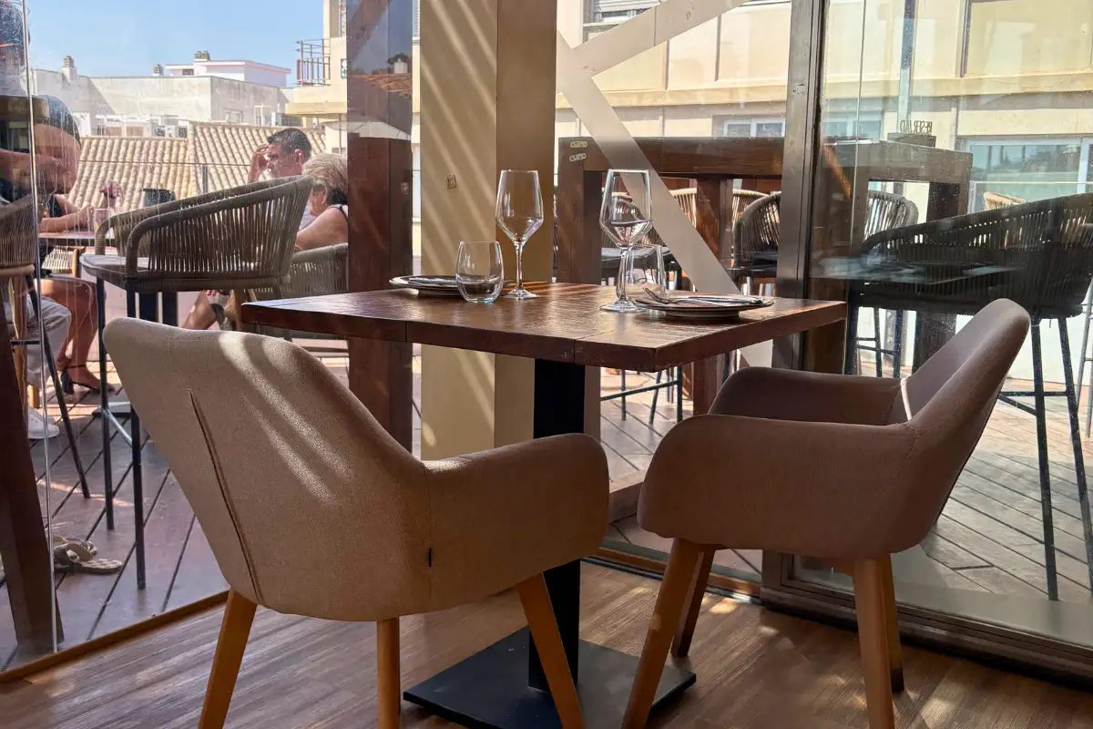 Armchairs at a window table with city views inside Terraza Catedral in Malaga