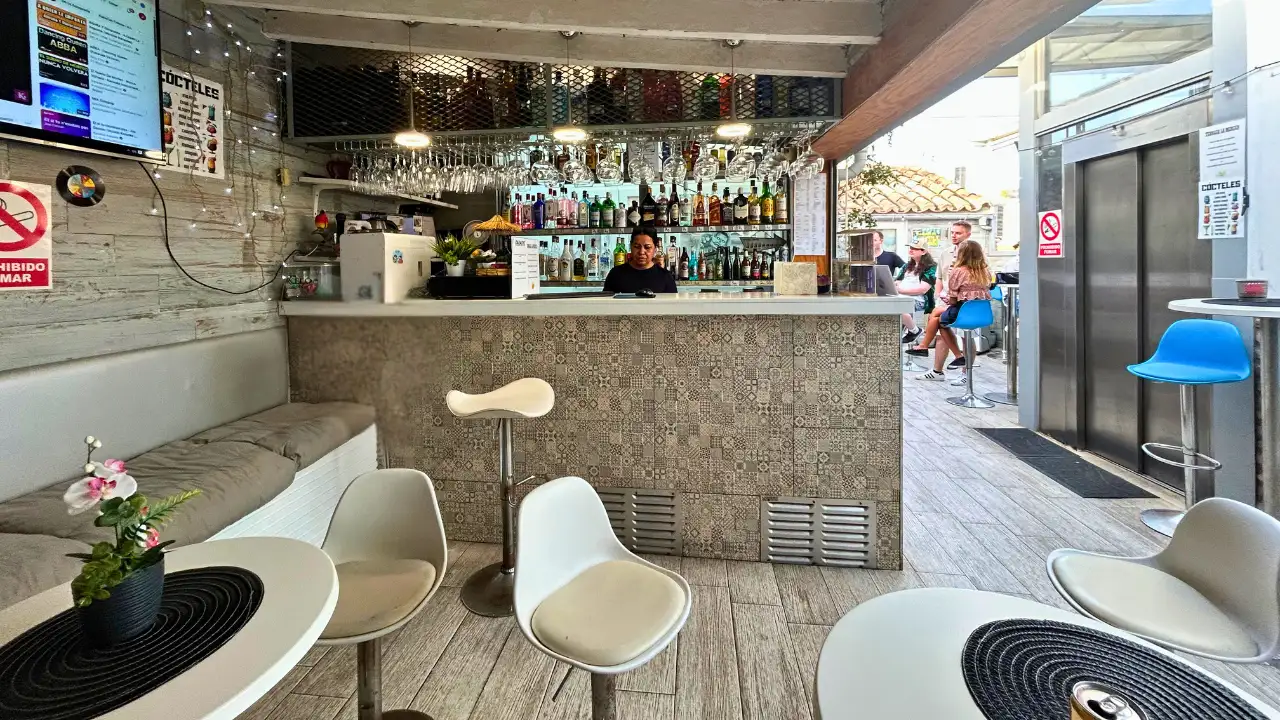 Indoor lounge bar with white stools and tables at Terraza La Merced in Malaga