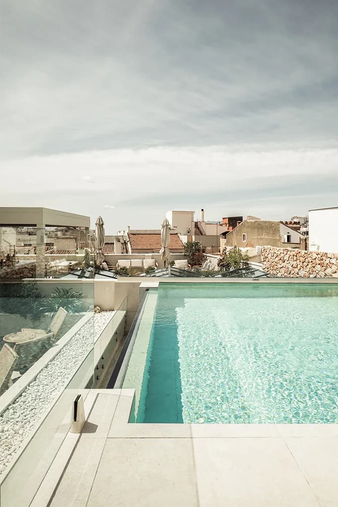 Rooftop plunge pool behind a glass railing overlooking Malaga old town rooftops at Well and Come
