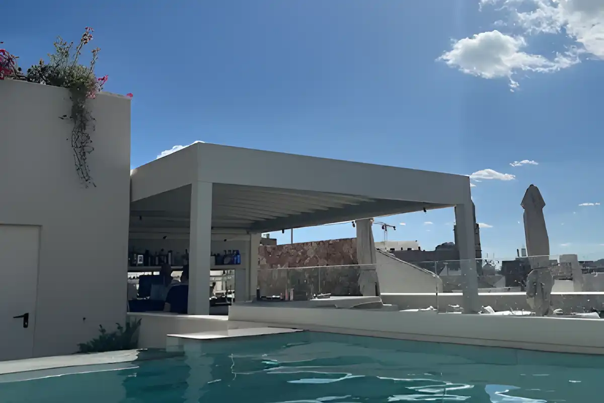 Rooftop pool and white pergola under blue sky at Well and Come Malaga