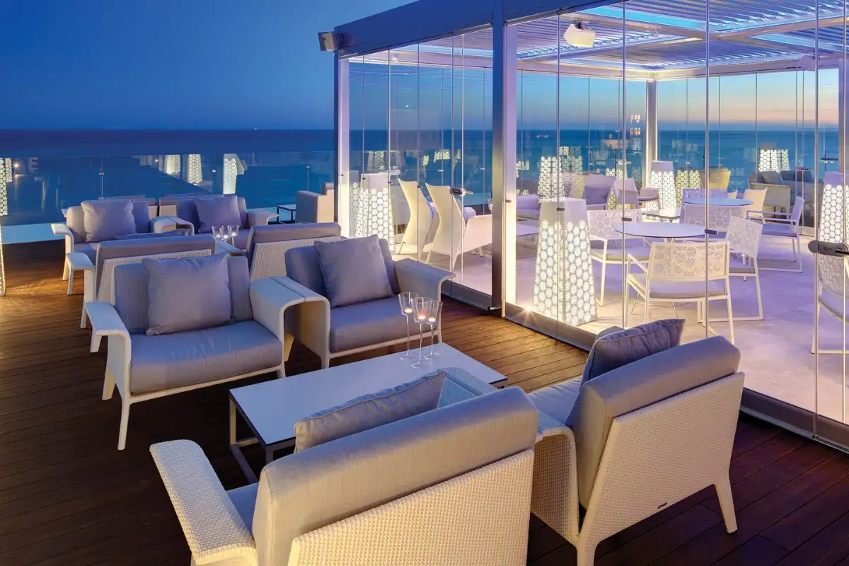 Pale sofas and lounge seating lit at night on The Belvue rooftop Marbella