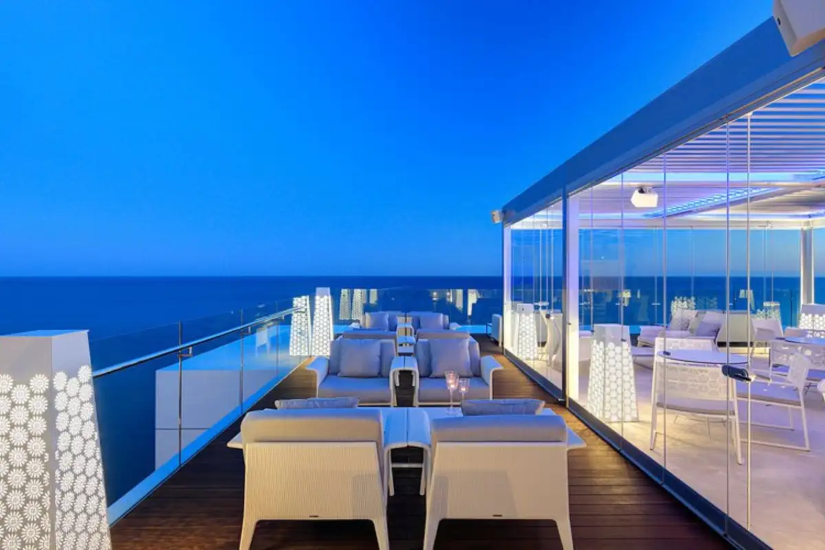 Dining tables along a sea-view terrace at dusk at The Belvue Marbella