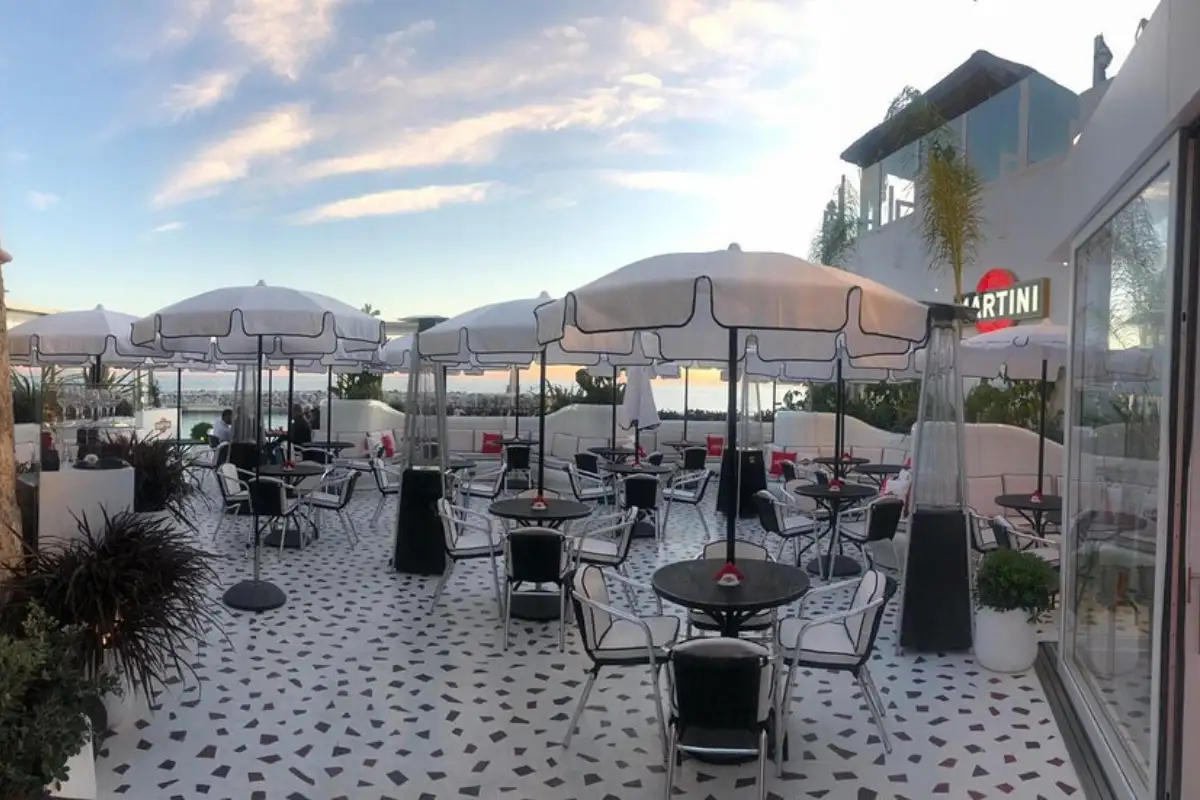 Tables and parasols on the tiled terrace at dusk, Martini Bar in Marbella
