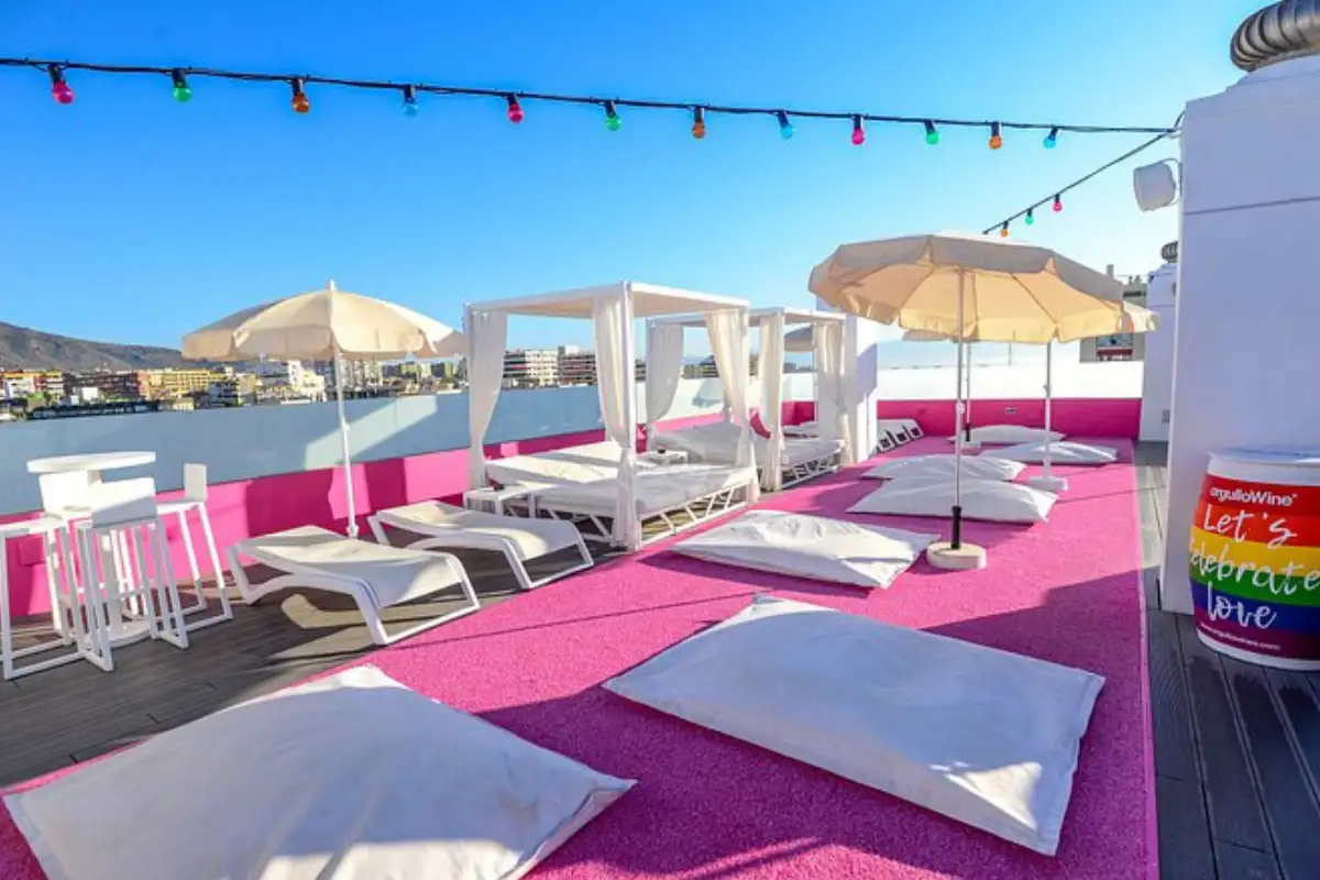 Pink-floored rooftop with white sunbeds and parasols at Hotel Ritual Torremolinos