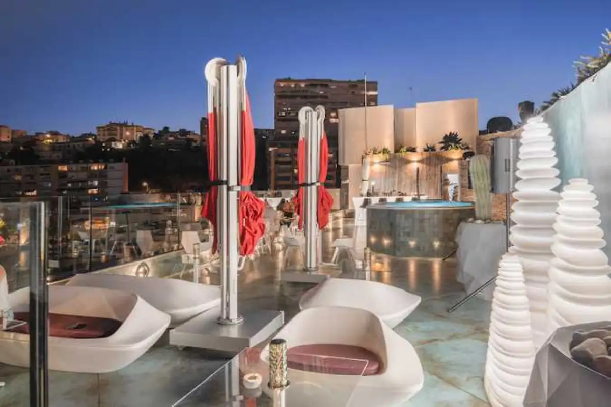 Set dining tables with red columns at dusk on Space Monkey rooftop Torremolinos