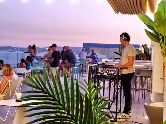 Guests at the bar and tables at dusk on the rooftop at Nix Sky Bar, Benalmadena