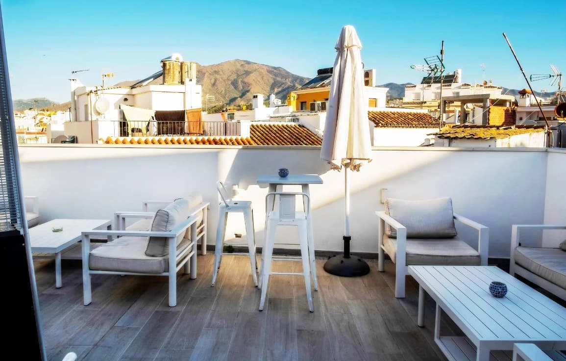Sunlit rooftop terrace with parasol and mountain backdrop at The Old Town Hotel, Estepona