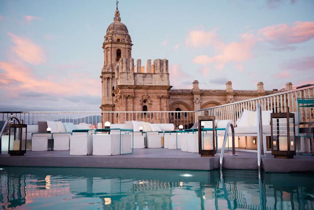 Rooftop pool at dusk with Malaga Cathedral glowing pink behind it