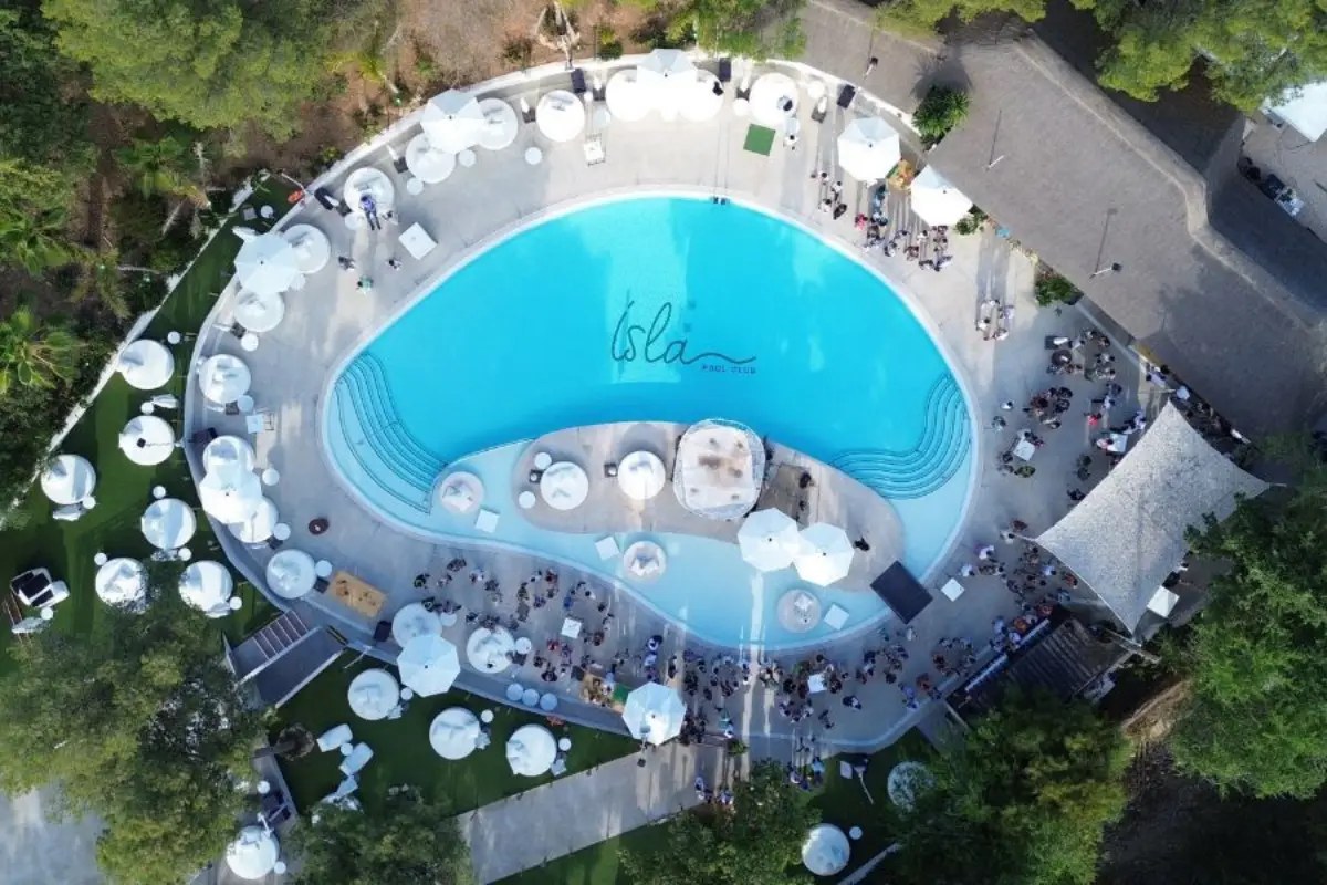 Aerial view of the curved pool and white umbrellas at Isla Pool Club in Malaga