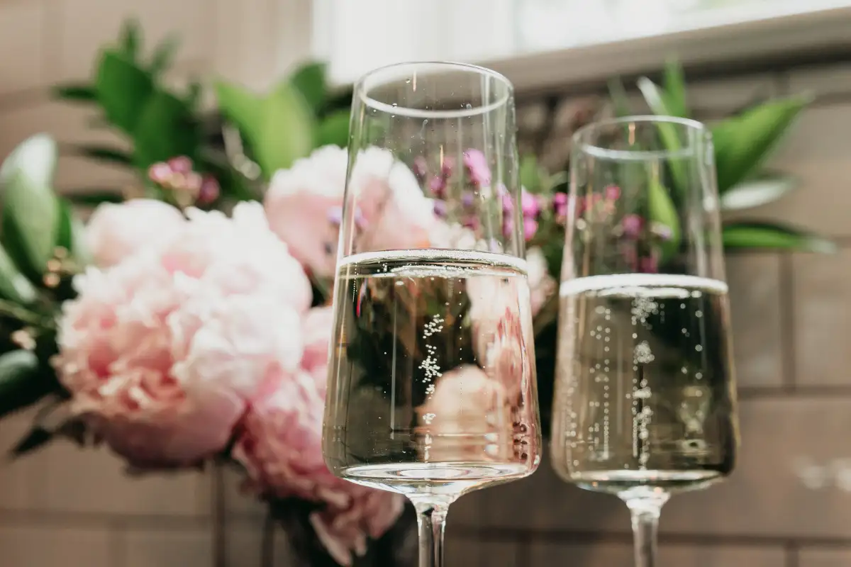 Two glasses of cava beside pink peonies at Parador de Malaga Gibralfaro