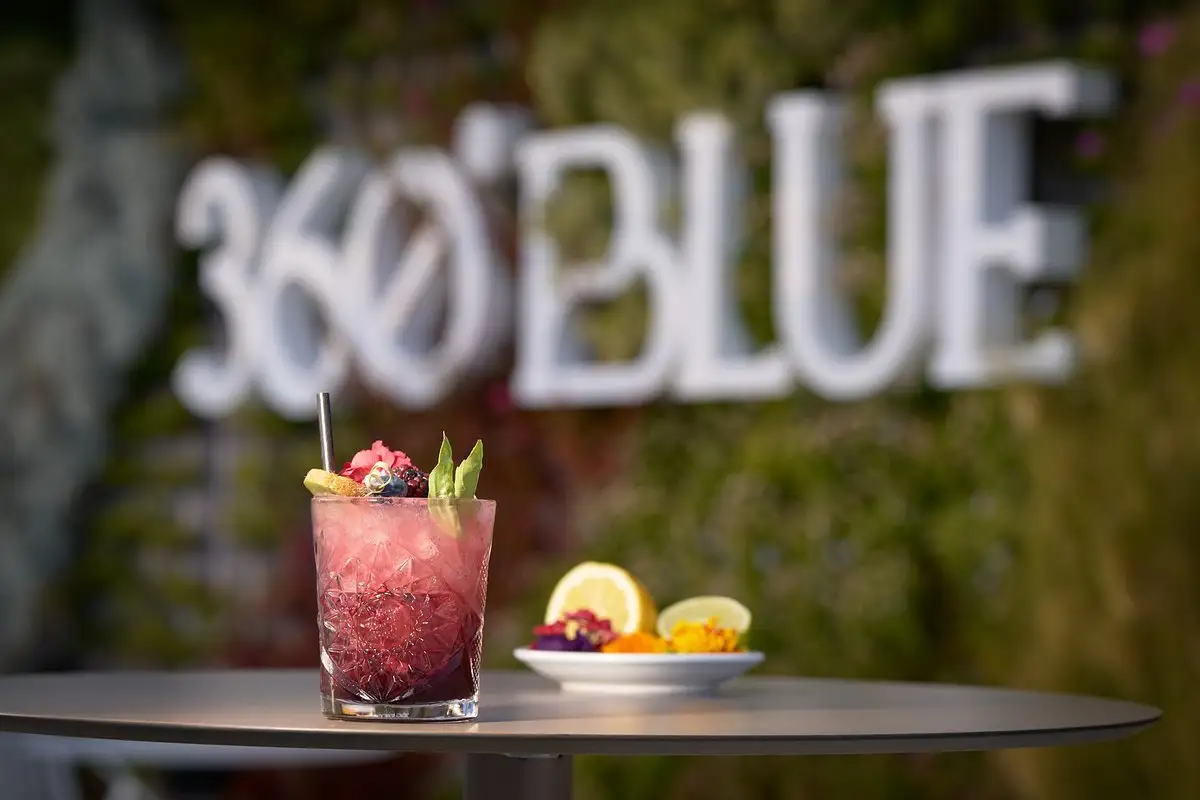 Berry cocktail and fruit plate before the 360 Blue sign in Marbella