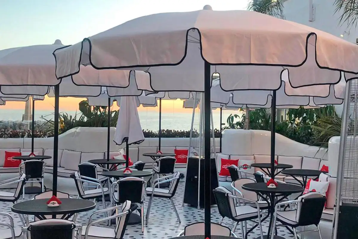 Outdoor tables under parasols at dusk on the Martini Bar terrace in Marbella