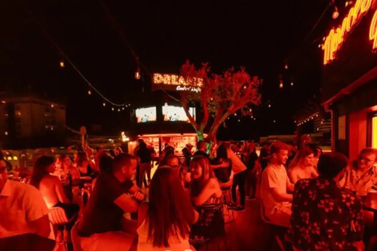 Lively night crowd under red lighting at Clock Tower rooftop in Torremolinos