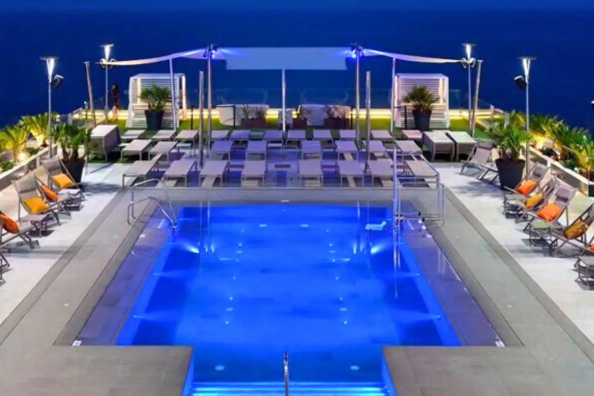 Illuminated rooftop pool with loungers at dusk at Sky and Sea Torremolinos