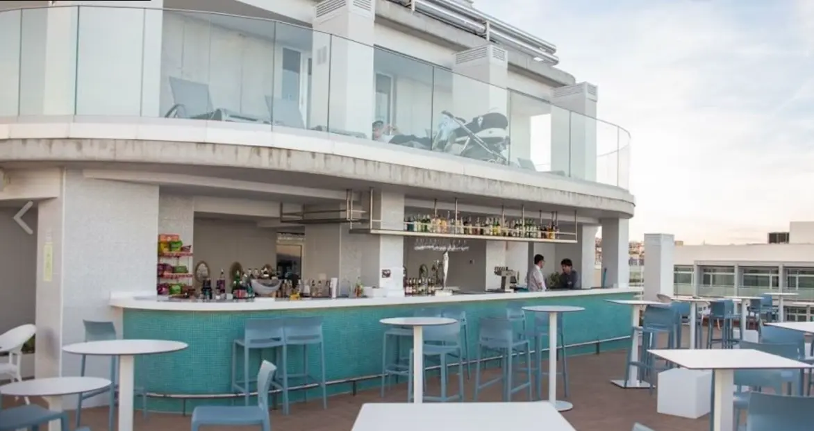 Curved white rooftop bar with turquoise counter and high tables at Celeste Skybar, Benalmadena