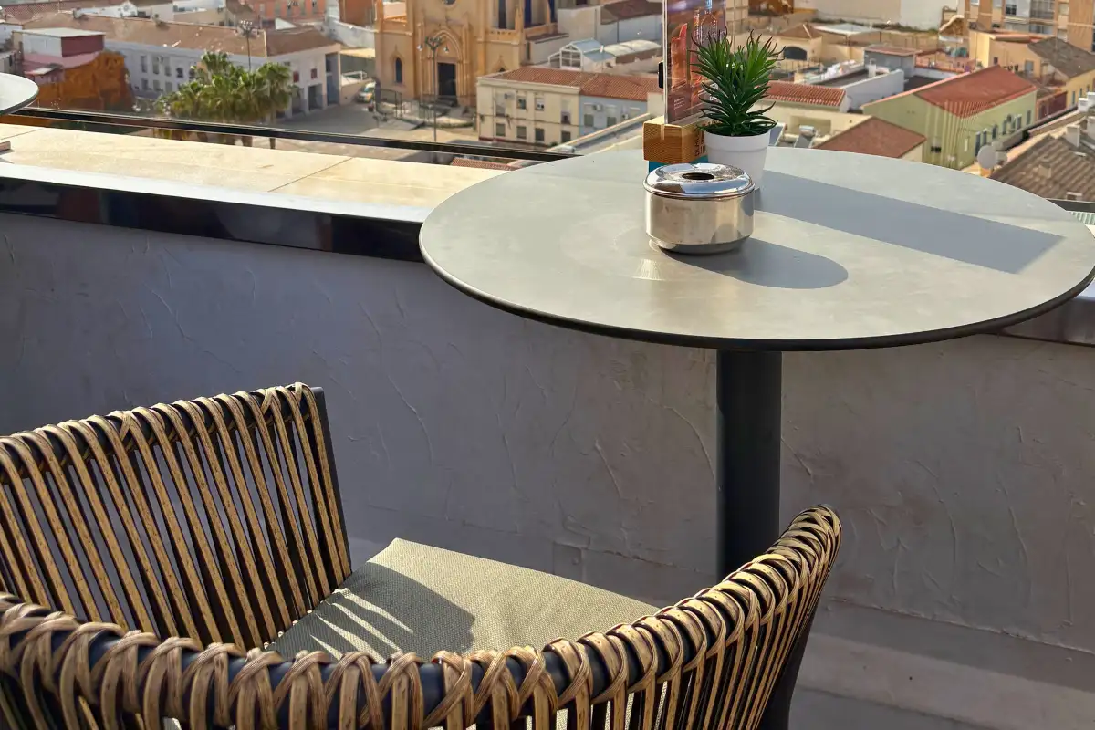Woven chair and table overlooking Malaga rooftops at Aurea terrace