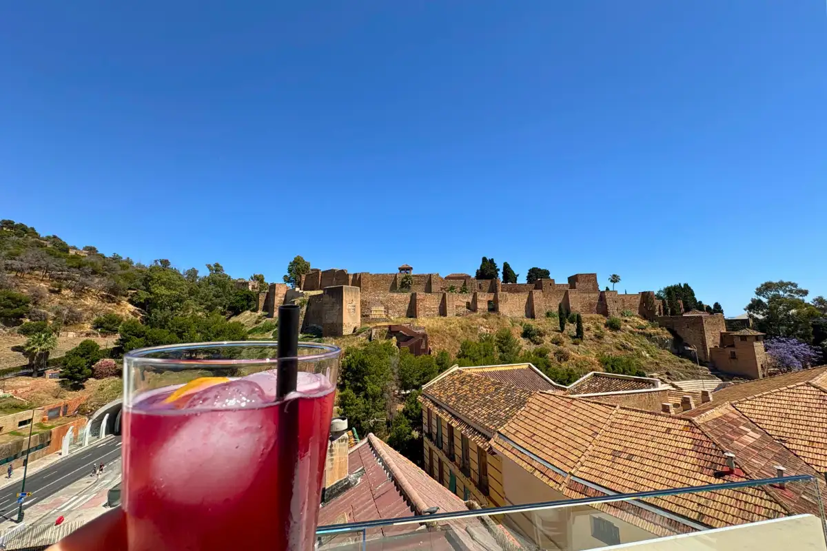 Red cocktail held up to the Alcazaba fortress view at La Terraza de Alcazaba in Malaga
