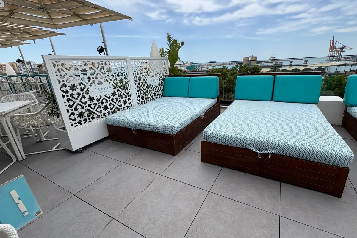 Turquoise-cushioned daybeds and a carved screen on La Terraza de Valeria rooftop in Malaga
