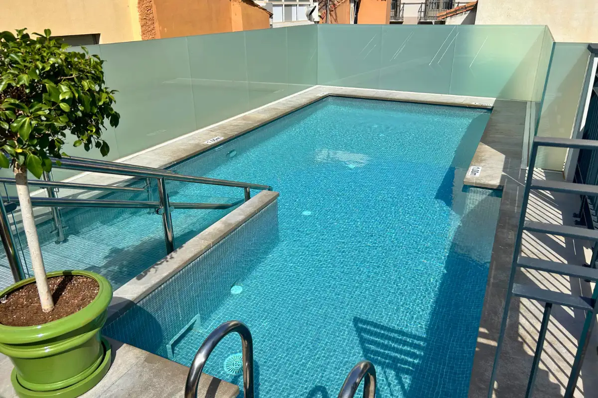 Turquoise rooftop pool with potted lemon tree at Palacio Solecio in Malaga