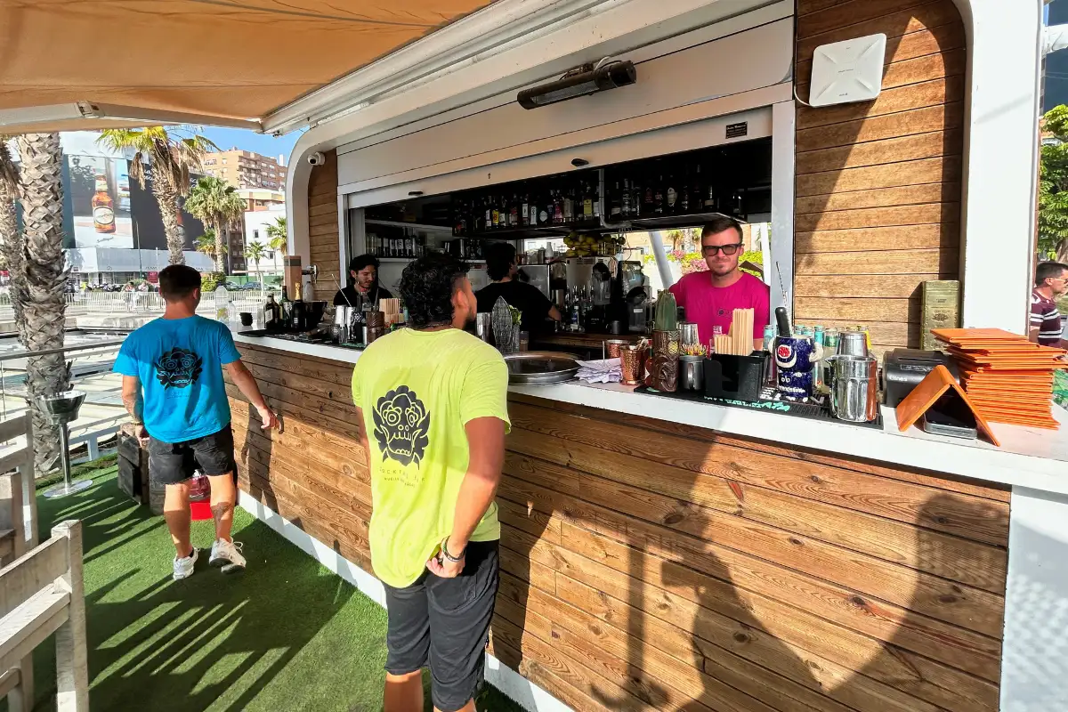 Wooden bar counter with bartender mixing drinks at Nusa, Muelle Uno, Malaga